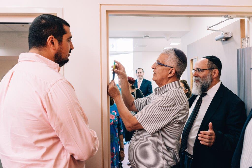 Kalman Samuels and Gideon Shalom affixing a Mezuzah on a classroom